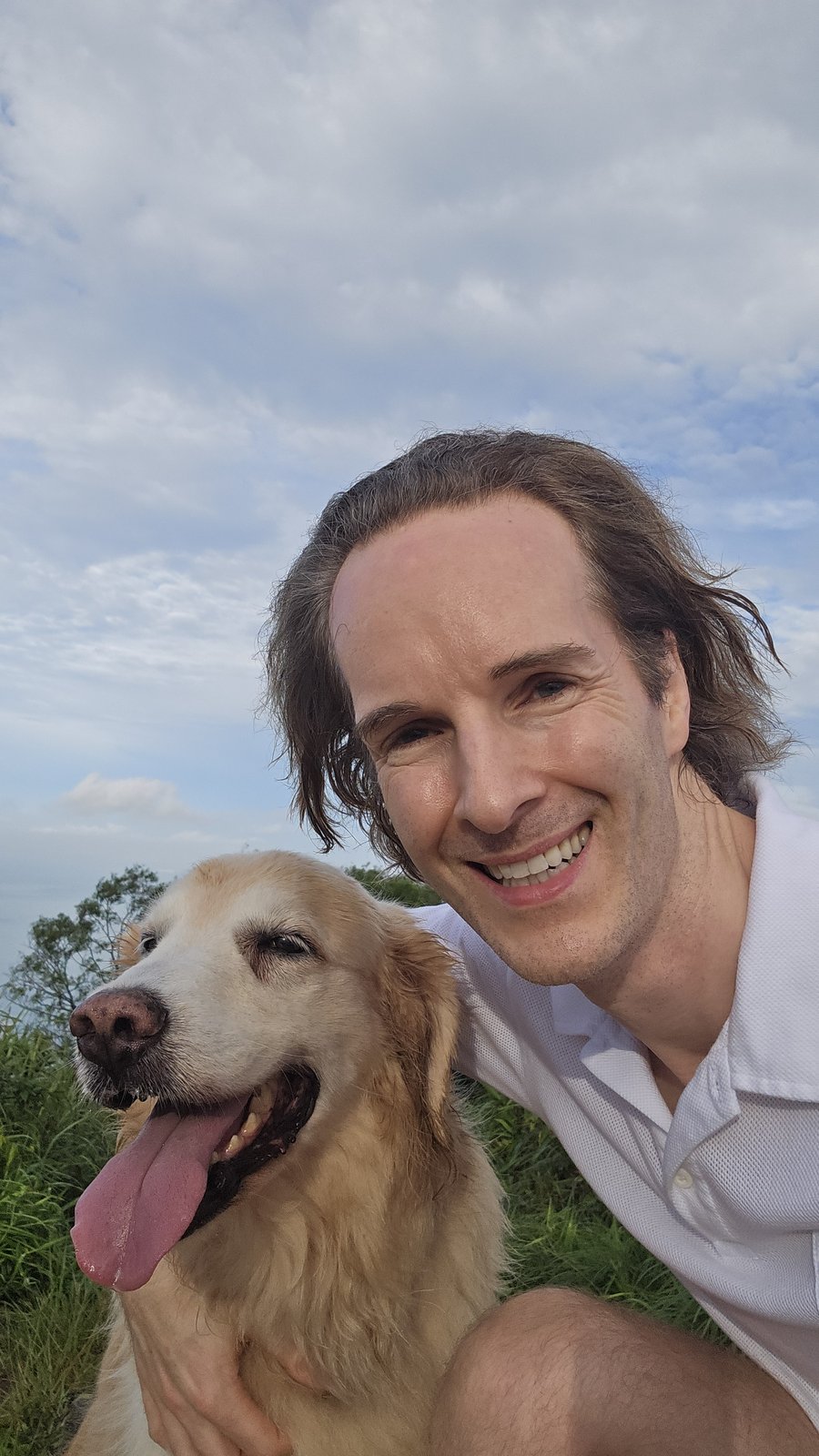 Felix Prehn smiling with a golden retriever in a meadow