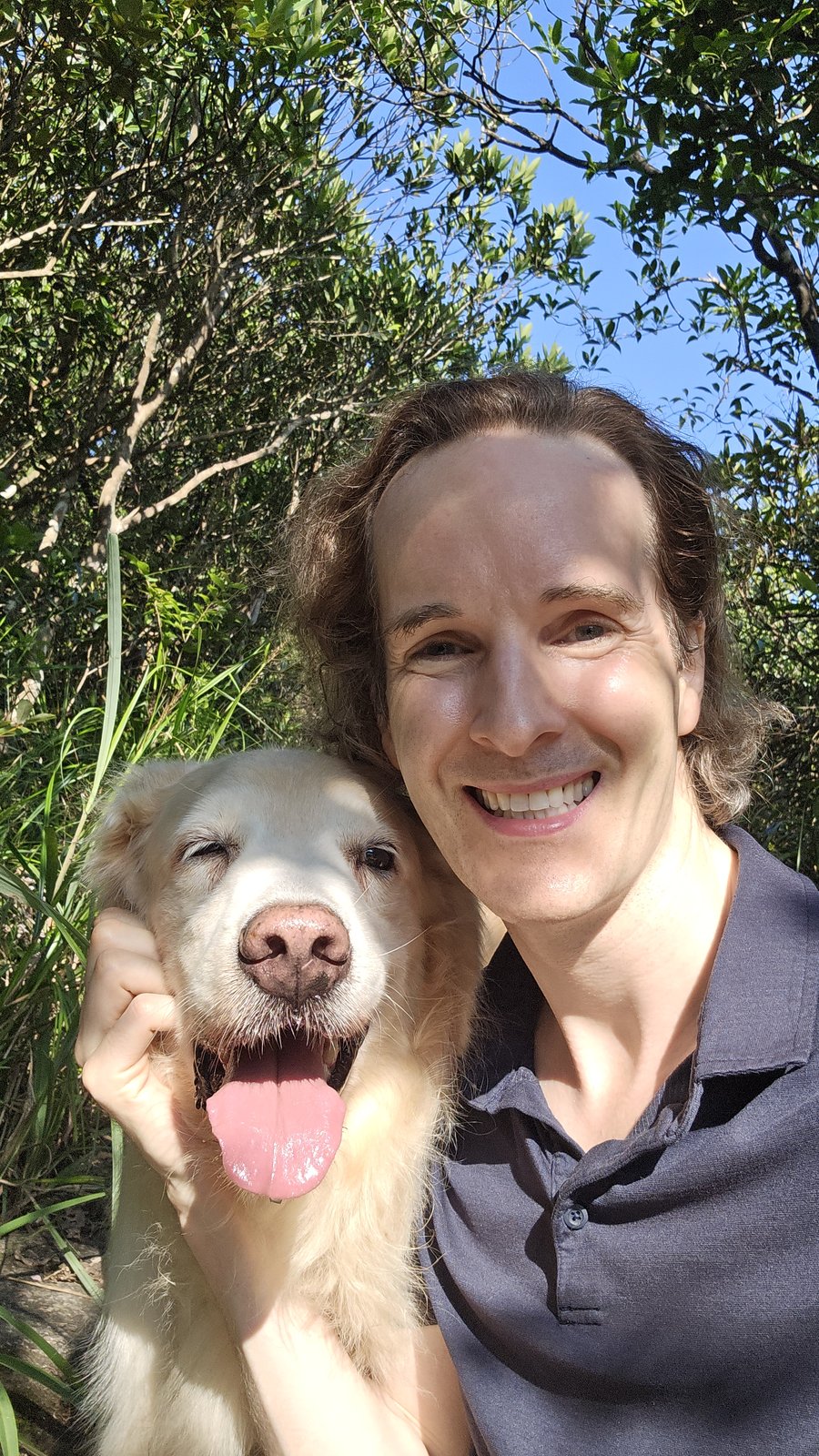 Felix Prehn outdoors with a golden retriever among the trees
