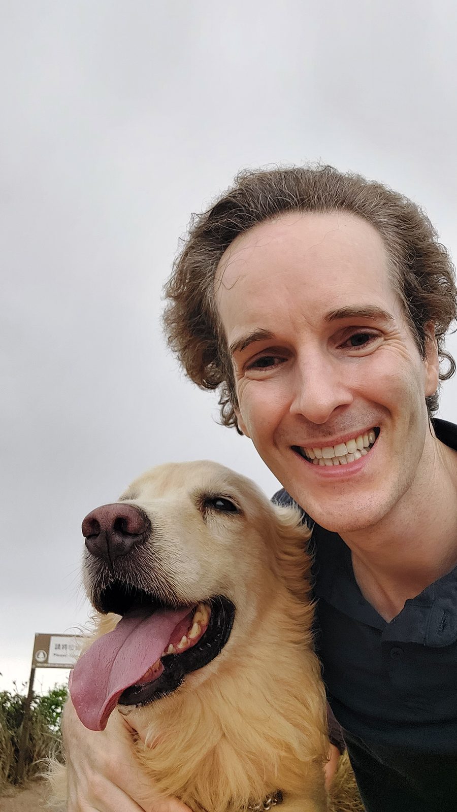 Nikolas Prehn (Felix Nikolas Prehn), close up with his golden retriever Winston under a grey sky