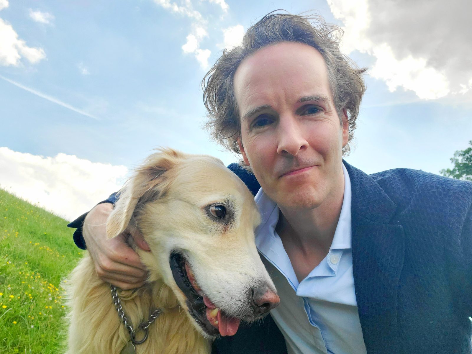 Nikolas Prehn (Felix Nikolas Prehn), in a navy jacket with Winston on a grassy hill